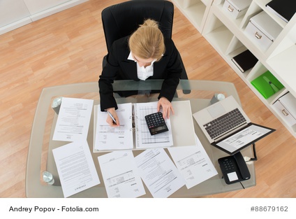 Businesswoman Calculating Invoices In Office